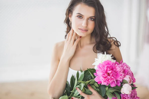 Young attractive woman with pink and white peony flowers