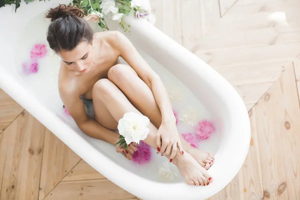 花とミルクの若い美しい女性入浴 — ストック写真