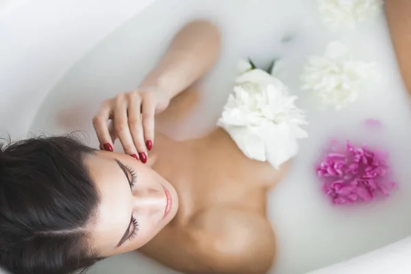 花とミルクの若い美しい女性入浴 — ストック写真
