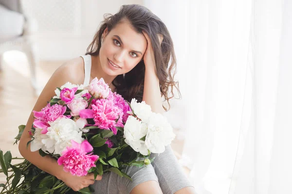 Young attractive woman with pink and white peony flowers