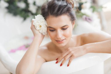 Genç güzel kadın alarak banyo çiçek ve süt ile
