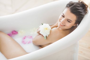 Genç güzel kadın alarak banyo çiçek ve süt ile