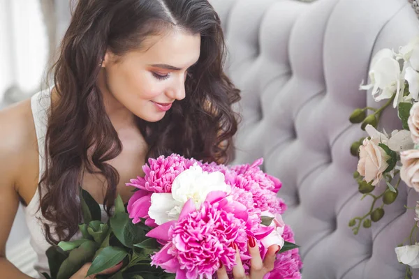 Young attractive woman with pink and white peony flowers