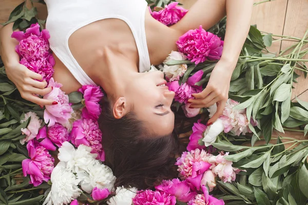 Young attractive woman with pink and white peony flowers