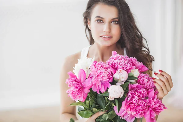 Young attractive woman with pink and white peony flowers