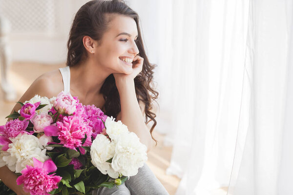 Young attractive woman with pink and white peony flowers