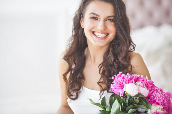 Young attractive woman with pink and white peony flowers