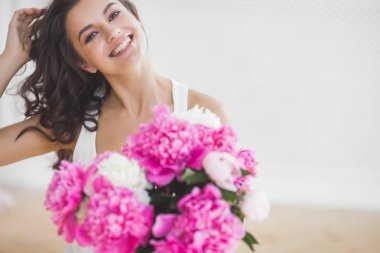 Pembe ve beyaz şakayık çiçekleri olan çekici kadın