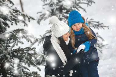 Genç güzel anne ve küçük kızı kışın dışarıda eğleniyor. Çocuk ve kar, doğa ile oynarken annesi güzel. Parçalı