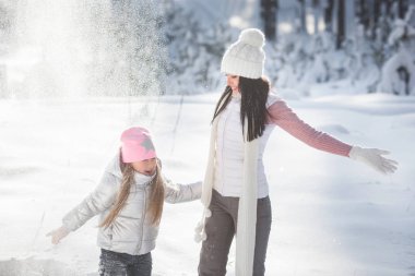 Genç güzel anne ve küçük kızı kışın dışarıda eğleniyor. Çocuk ve kar, doğa ile oynarken annesi güzel. Parçalı