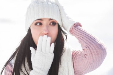 Kışın açık havada sürpriz genç kadın. Chocked adı ne? Örgü şapka, eldiven ve atkı giyen kadın