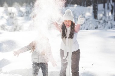 Genç güzel anne ve küçük kızı kışın dışarıda eğleniyor. Çocuk ve kar, doğa ile oynarken annesi güzel. Parçalı