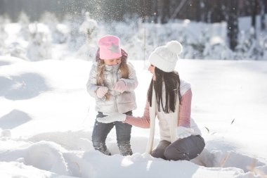 Genç güzel anne ve küçük kızı kışın dışarıda eğleniyor. Çocuk ve kar, doğa ile oynarken annesi güzel. Parçalı