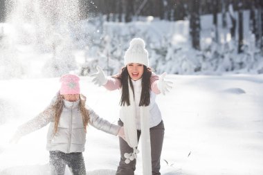 Genç güzel anne ve küçük kızı kışın dışarıda eğleniyor. Çocuk ve kar, doğa ile oynarken annesi güzel. Parçalı