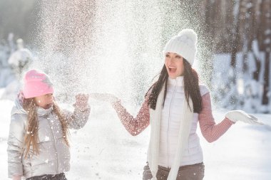 Genç güzel anne ve küçük kızı kışın dışarıda eğleniyor. Çocuk ve kar, doğa ile oynarken annesi güzel. Parçalı