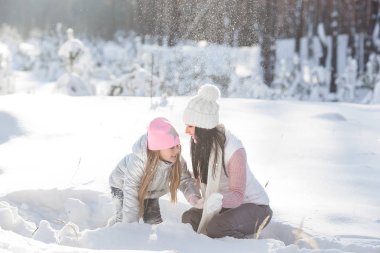 Genç güzel anne ve küçük kızı kışın dışarıda eğleniyor. Çocuk ve kar, doğa ile oynarken annesi güzel. Parçalı