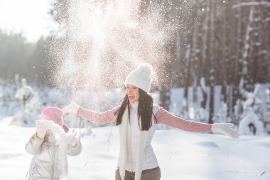 Genç güzel anne ve küçük kızı kışın dışarıda eğleniyor. Çocuk ve kar, doğa ile oynarken annesi güzel. Parçalı