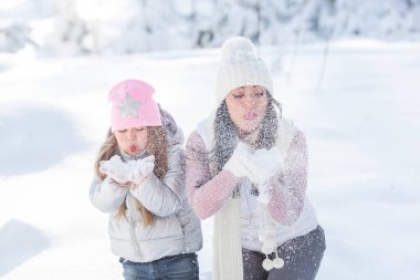 Genç güzel anne ve küçük kızı kışın dışarıda eğleniyor. Çocuk ve kar, doğa ile oynarken annesi güzel. Parçalı