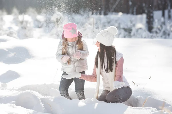 Genç güzel anne ve küçük kızı kışın dışarıda eğleniyor. Çocuk ve kar, doğa ile oynarken annesi güzel. Parçalı