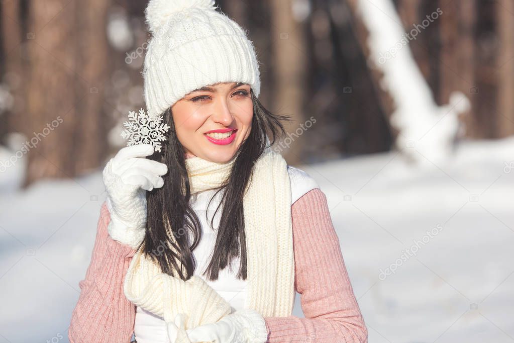 Portrait of young cheerful woman with snowflake in winter background