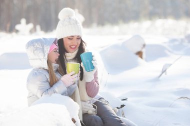 Anne ve kızı kış döneminde dışarıda eğleniyor. Güzel aile içme çay ve kakao