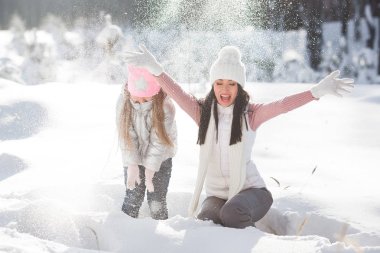 Genç güzel anne ve küçük kızı kışın dışarıda eğleniyor. Çocuk ve kar, doğa ile oynarken annesi güzel. Parçalı