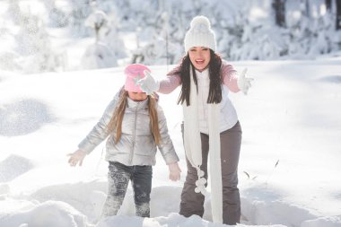 Genç güzel anne ve küçük kızı kışın dışarıda eğleniyor. Çocuk ve kar, doğa ile oynarken annesi güzel. Parçalı