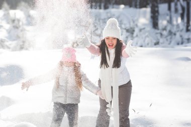Genç güzel anne ve küçük kızı kışın dışarıda eğleniyor. Çocuk ve kar, doğa ile oynarken annesi güzel. Parçalı