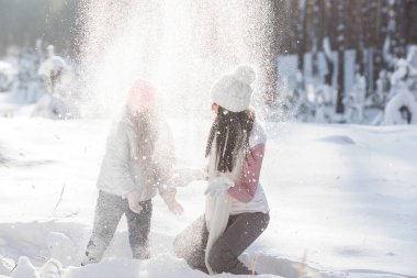 Genç güzel anne ve küçük kızı kışın dışarıda eğleniyor. Çocuk ve kar, doğa ile oynarken annesi güzel. Parçalı