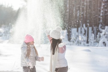 Genç güzel anne ve küçük kızı kışın dışarıda eğleniyor. Çocuk ve kar, doğa ile oynarken annesi güzel. Parçalı