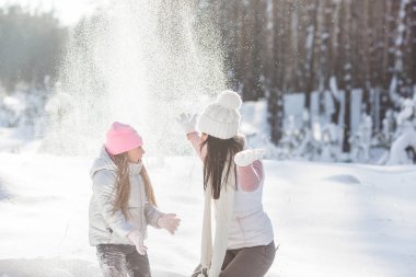 Genç güzel anne ve küçük kızı kışın dışarıda eğleniyor. Çocuk ve kar, doğa ile oynarken annesi güzel. Parçalı