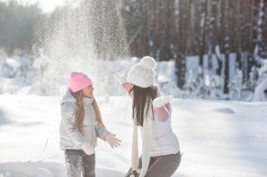 Genç güzel anne ve küçük kızı kışın dışarıda eğleniyor. Çocuk ve kar, doğa ile oynarken annesi güzel. Parçalı