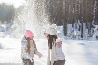 Genç güzel anne ve küçük kızı kışın dışarıda eğleniyor. Çocuk ve kar, doğa ile oynarken annesi güzel. Parçalı