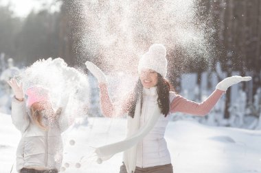 Genç güzel anne ve küçük kızı kışın dışarıda eğleniyor. Çocuk ve kar, doğa ile oynarken annesi güzel. Parçalı