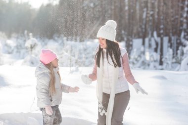 Genç güzel anne ve küçük kızı kışın dışarıda eğleniyor. Çocuk ve kar, doğa ile oynarken annesi güzel. Parçalı
