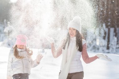 Genç güzel anne ve küçük kızı kışın dışarıda eğleniyor. Çocuk ve kar, doğa ile oynarken annesi güzel. Parçalı