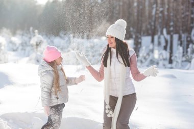 Genç güzel anne ve küçük kızı kışın dışarıda eğleniyor. Çocuk ve kar, doğa ile oynarken annesi güzel. Parçalı