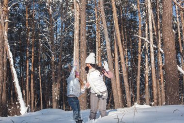 Genç güzel anne ve küçük kızı kışın dışarıda eğleniyor. Çocuk ve kar, doğa ile oynarken annesi güzel. Parçalı