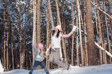 Genç güzel anne ve küçük kızı kışın dışarıda eğleniyor. Çocuk ve kar, doğa ile oynarken annesi güzel. Parçalı