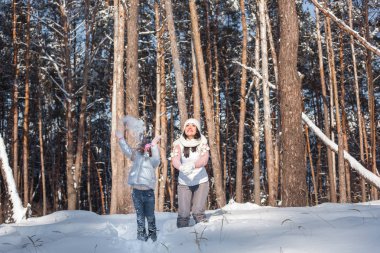 Genç güzel anne ve küçük kızı kışın dışarıda eğleniyor. Çocuk ve kar, doğa ile oynarken annesi güzel. Parçalı
