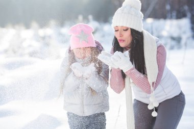 Genç güzel anne ve küçük kızı kışın dışarıda eğleniyor. Çocuk ve kar, doğa ile oynarken annesi güzel. Parçalı