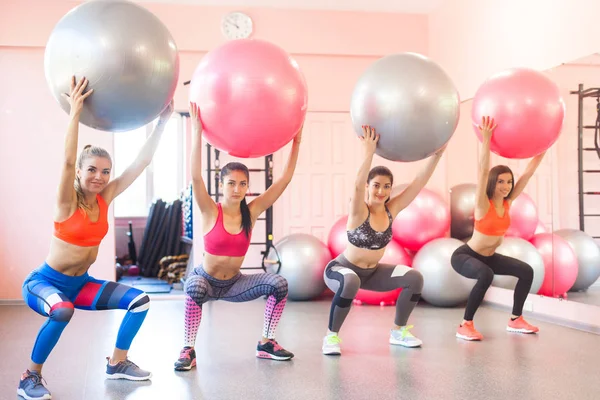 Group of young women doing exercises with fitballs. Pair exercises for fitness
