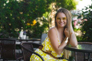 Çekici kadın kafeteryada. Sarı elbise giyen genç bayan. Neşeli kız açık havada içki kahve