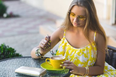 Kafede kahve fincan ile oturan genç çekici kadın portresi. Aromatik çay içme kadın. Güzel kızın sevgilisi bekleyen kafeteryada resmi.