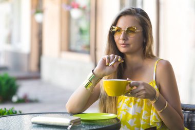 Kafede kahve fincan ile oturan genç çekici kadın portresi. Aromatik çay içme kadın. Güzel kızın sevgilisi bekleyen kafeteryada resmi.