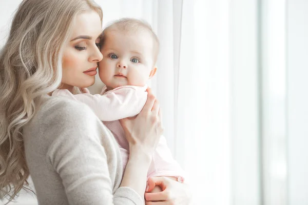 Genç çekici kaygı-in küçük bebek kızı anne. Güzel anne ve kızı yatak odasında kapalı. Sevgi dolu aile. Çekici anne çocuğunu tutan.