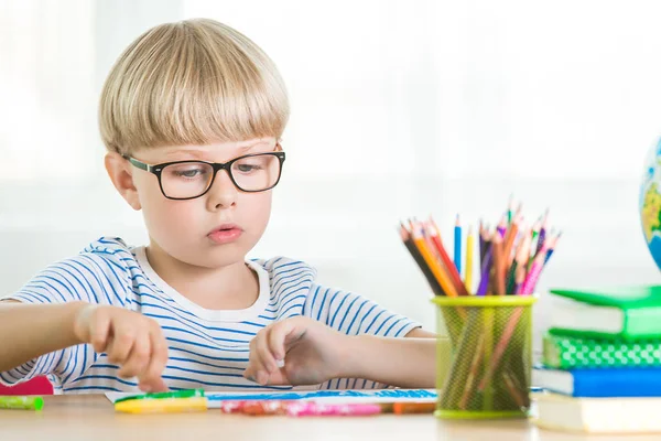 Cute child study at home. Little boy with globe and books indoors. Adorable student learning lessons and doing tasks