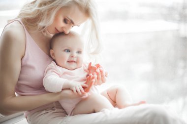 Genç çekici kaygı-in küçük bebek kızı anne. Güzel anne ve kızı yatak odasında kapalı. Sevgi dolu aile. Çekici anne çocuğunu tutan.