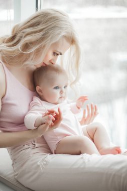 Genç çekici kaygı-in küçük bebek kızı anne. Güzel anne ve kızı yatak odasında kapalı. Sevgi dolu aile. Çekici anne çocuğunu tutan.
