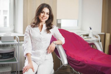 Genç, çekici bir kadın doktor. Klinikte üniforma giyen kadın portresi. Tıbbi ekipmanlı bir doktor. Salonunda kozmetik uzmanı.